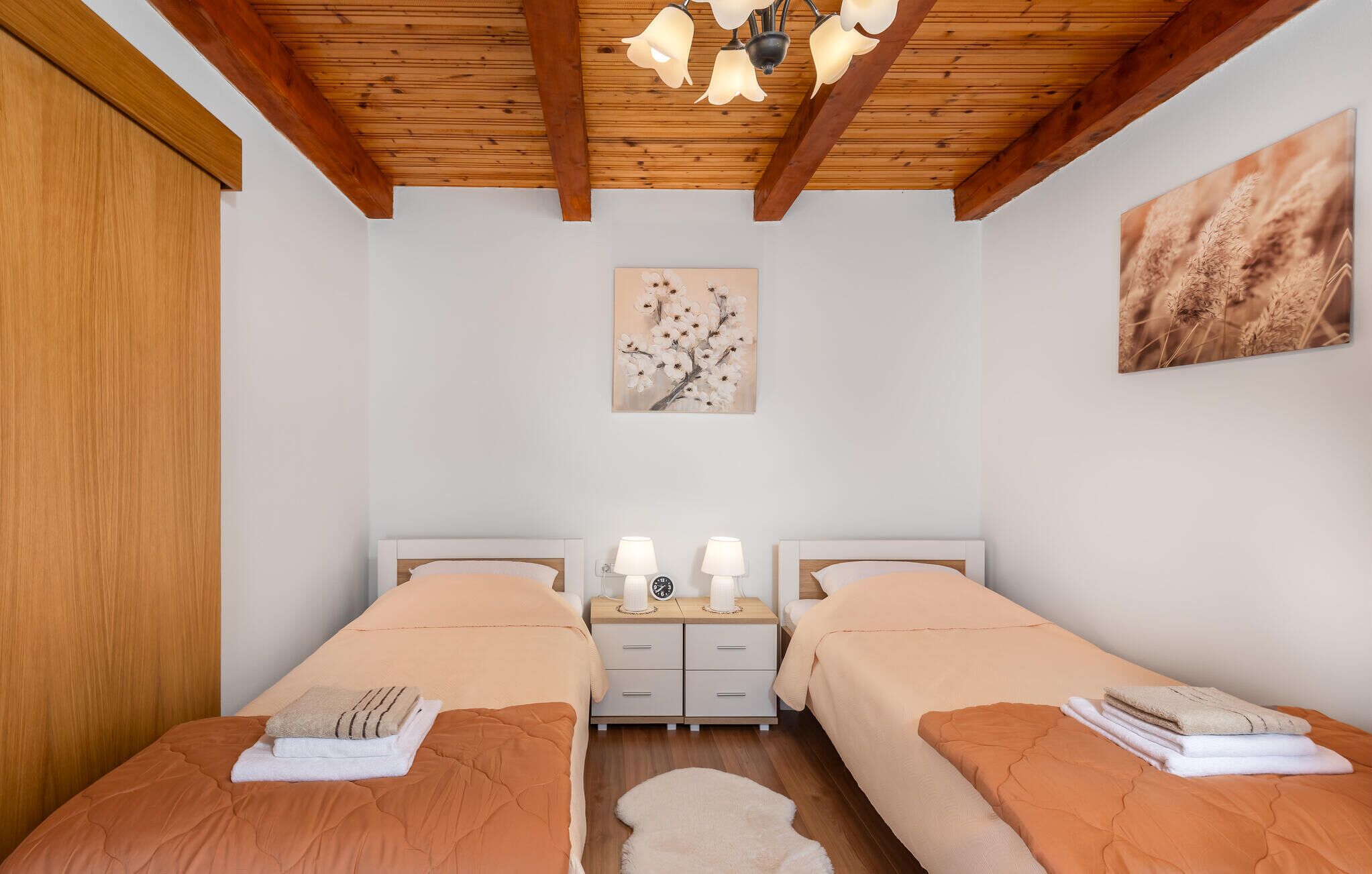 Une chambre avec deux lits, une table de chevet, une horloge et un luminaire au plafond.