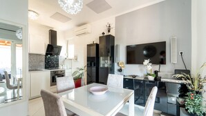 A modern kitchen with a black refrigerator, a microwave, and a stove. There is a dining table with chairs and a TV mounted on the wall. - Cozy apartment in Sali with WiFi (Sali)