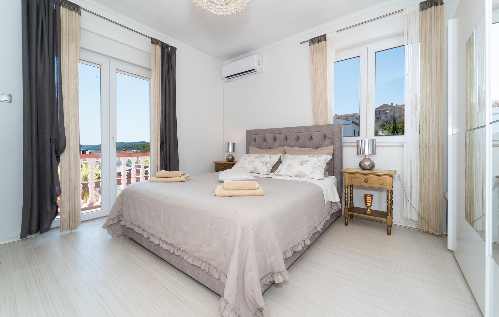 Um quarto espaçoso com uma cama grande, uma mesa de cabeceira e uma janela com cortinas.