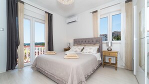 A spacious bedroom with a large bed, a nightstand, and a window with curtains. - Cozy apartment in Sali with WiFi (Sali)