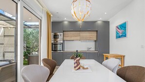 A modern kitchen with grey cabinets, a built-in oven, and a microwave. There is a dining table with chairs and a vase of flowers. - Lovely apartment in Murter with WiFi - CSV284 (Murter)