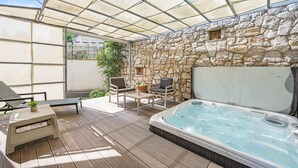 A patio area with a stone wall, a hot tub, and outdoor furniture. - Lovely apartment in Murter with WiFi - CSV284 (Murter)