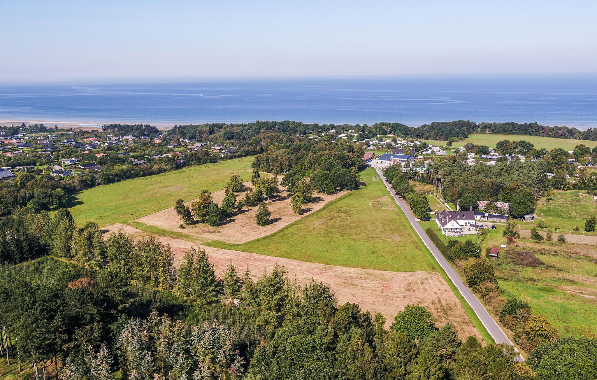 An aerial view of a residential area with houses, roads, and green fields.