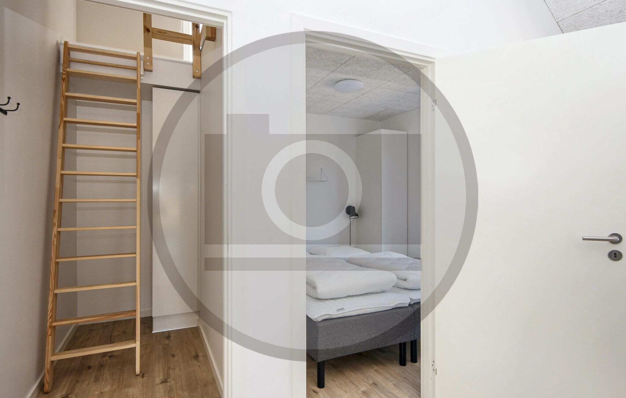 A compact room with a built-in bed, a wooden ladder, and a door.