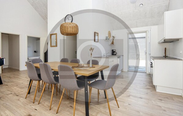 A modern kitchen with white cabinets, a wooden dining table, and grey chairs.