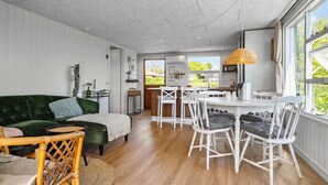 A cozy living room with a green sofa, white chairs, and a dining table. - 2 bedroom cozy home in Juelsminde (Juelsminde)