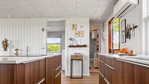 A kitchen with wooden cabinets, a central island, and a window providing natural light. - 2 bedroom cozy home in Juelsminde (Juelsminde)