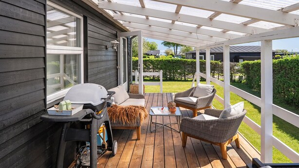 A covered patio with outdoor furniture, a grill, and a view of the surrounding garden and neighborhood. - 2 bedroom cozy home in Juelsminde (Juelsminde)