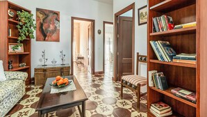 Una sala de estar con un sofá, una mesa baja con naranjas, una estantería y un cuadro en la pared.