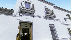 Un edificio blanco con balcón, puerta y ventana con reja de metal.