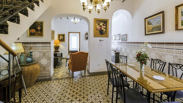Un comedor con piso estampado, una araña y una escalera.