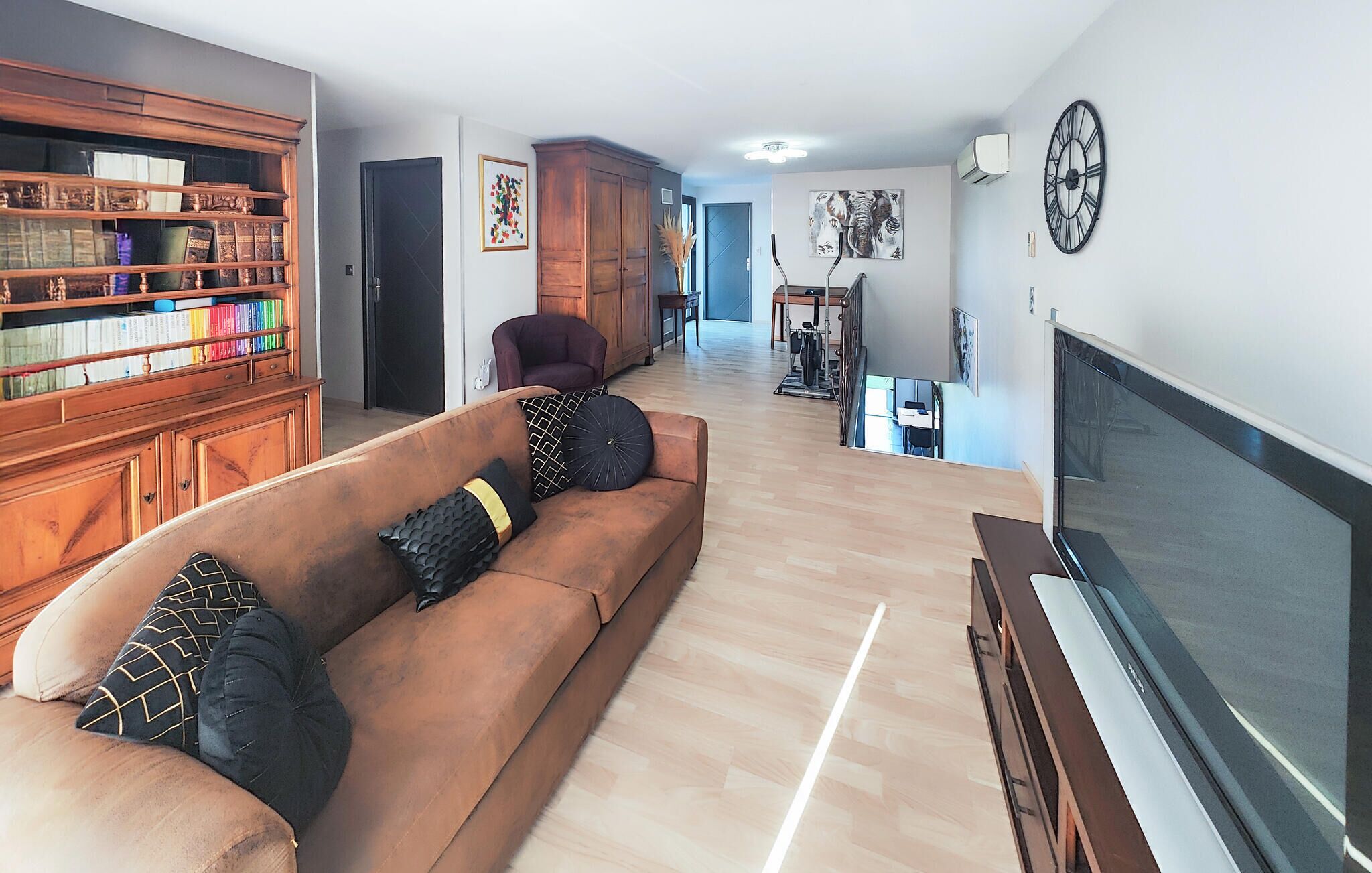 A living room with a sofa, a TV, a bookshelf, and a staircase leading to another room.