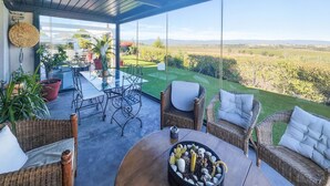 Une terrasse dotée de meubles en osier, une table agrémentée d’un cactus en guise de centre de table, et une vue sur un paysage verdoyant.