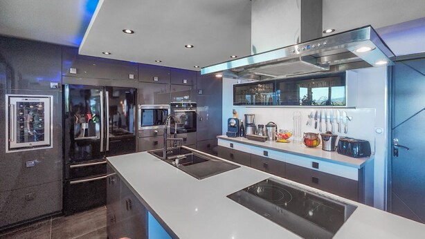 Une cuisine moderne dotée d’un îlot central, d’appareils électroménagers en acier inoxydable et de divers ustensiles de cuisine accrochés au mur.
