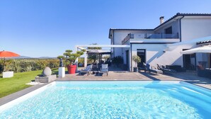 Une maison moderne dotée d’une piscine, d’un espace salon extérieur et d’un jardin.