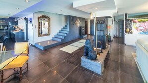 Un vaste espace de vie doté d’un haut plafond, d’un escalier et d’un coin repas avec une table et des chaises en verre.