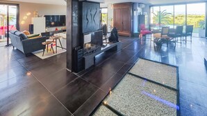 Un salon moderne doté d’une cheminée, d’un téléviseur et d’un coin repas offrant une vue sur l’extérieur.