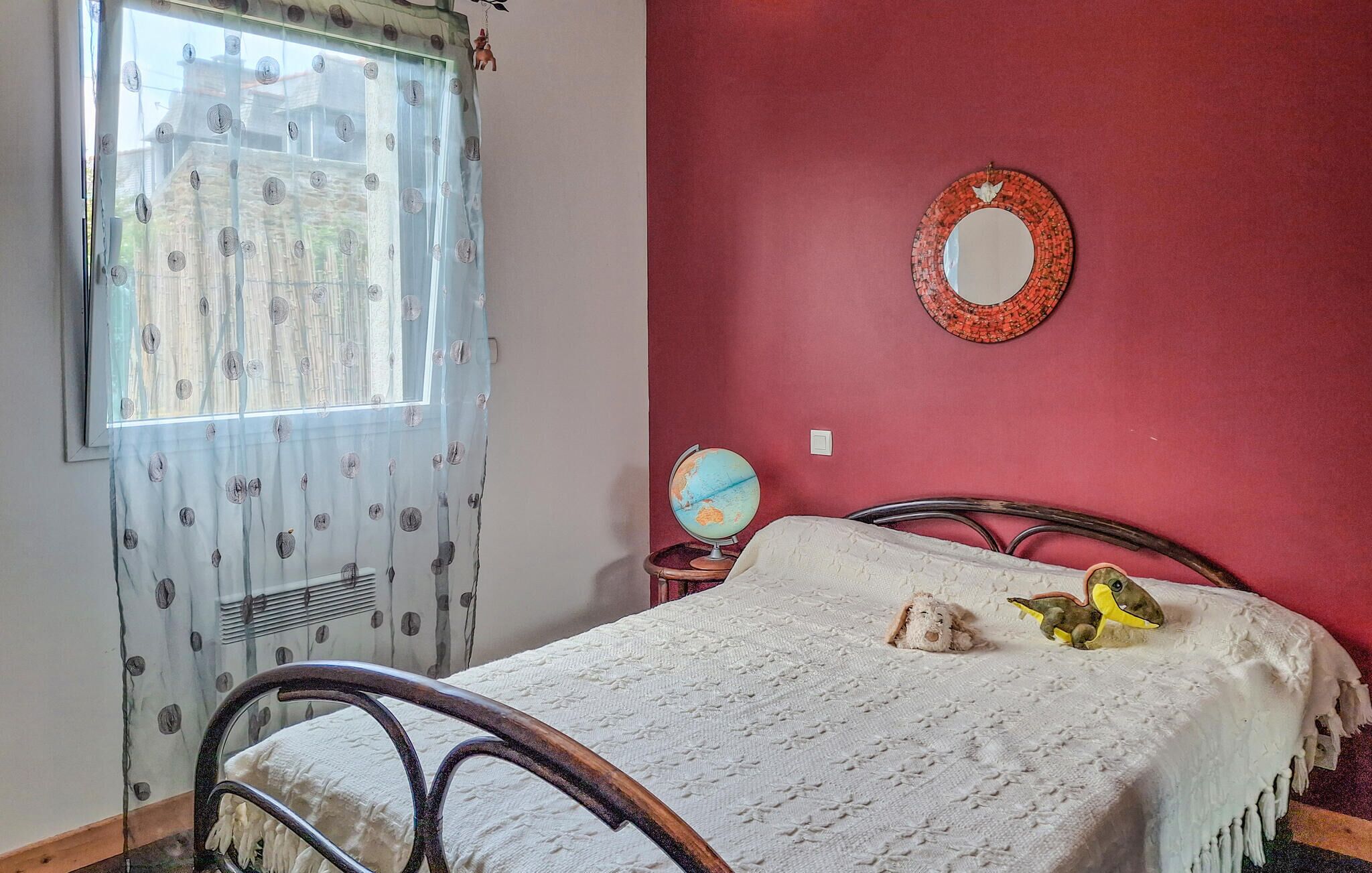 A bedroom with a bed, a globe, and a mirror on the wall.