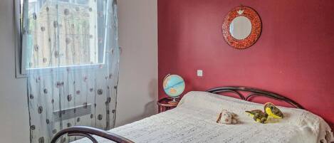 A bedroom with a bed, a globe, and a mirror on the wall.