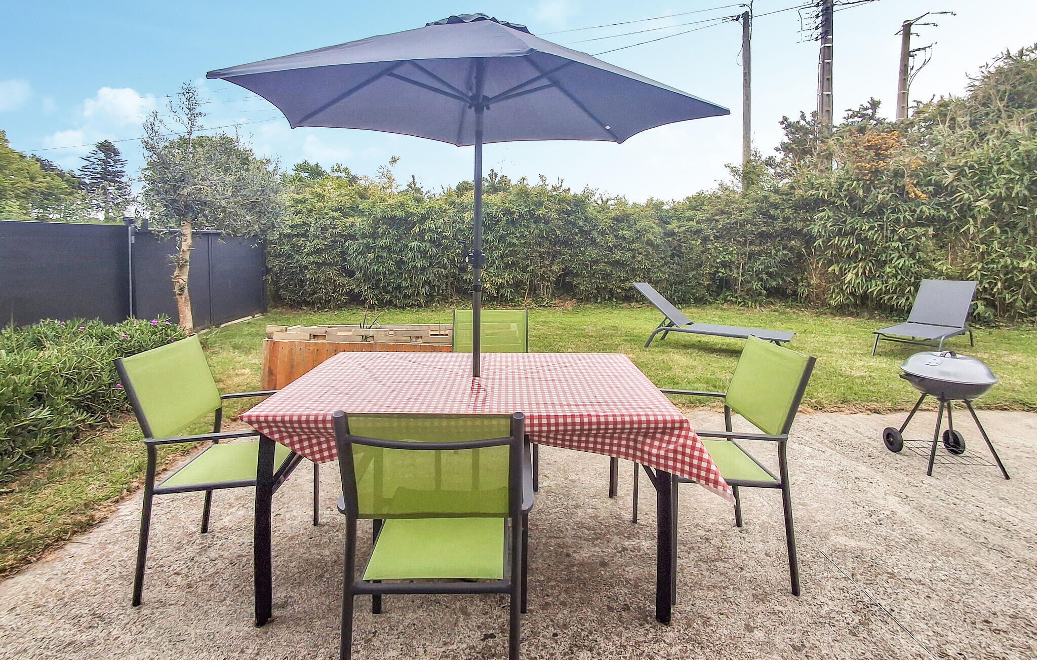 Un patio exterior con mesa y sillas, una parrilla y una silla de descanso.