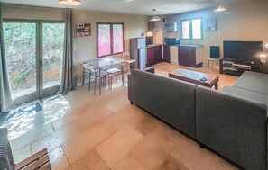 Un salon avec un canapé, une table à manger avec des chaises, un coin cuisine avec un réfrigérateur et un téléviseur.
