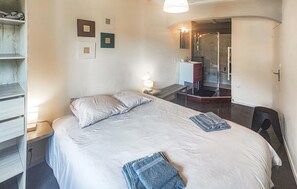 Une chambre à coucher avec un lit, une table de chevet, une lampe et une vue sur la salle de bain.