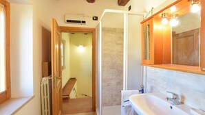 A bathroom with a white sink, wooden cabinets, and a shower area.