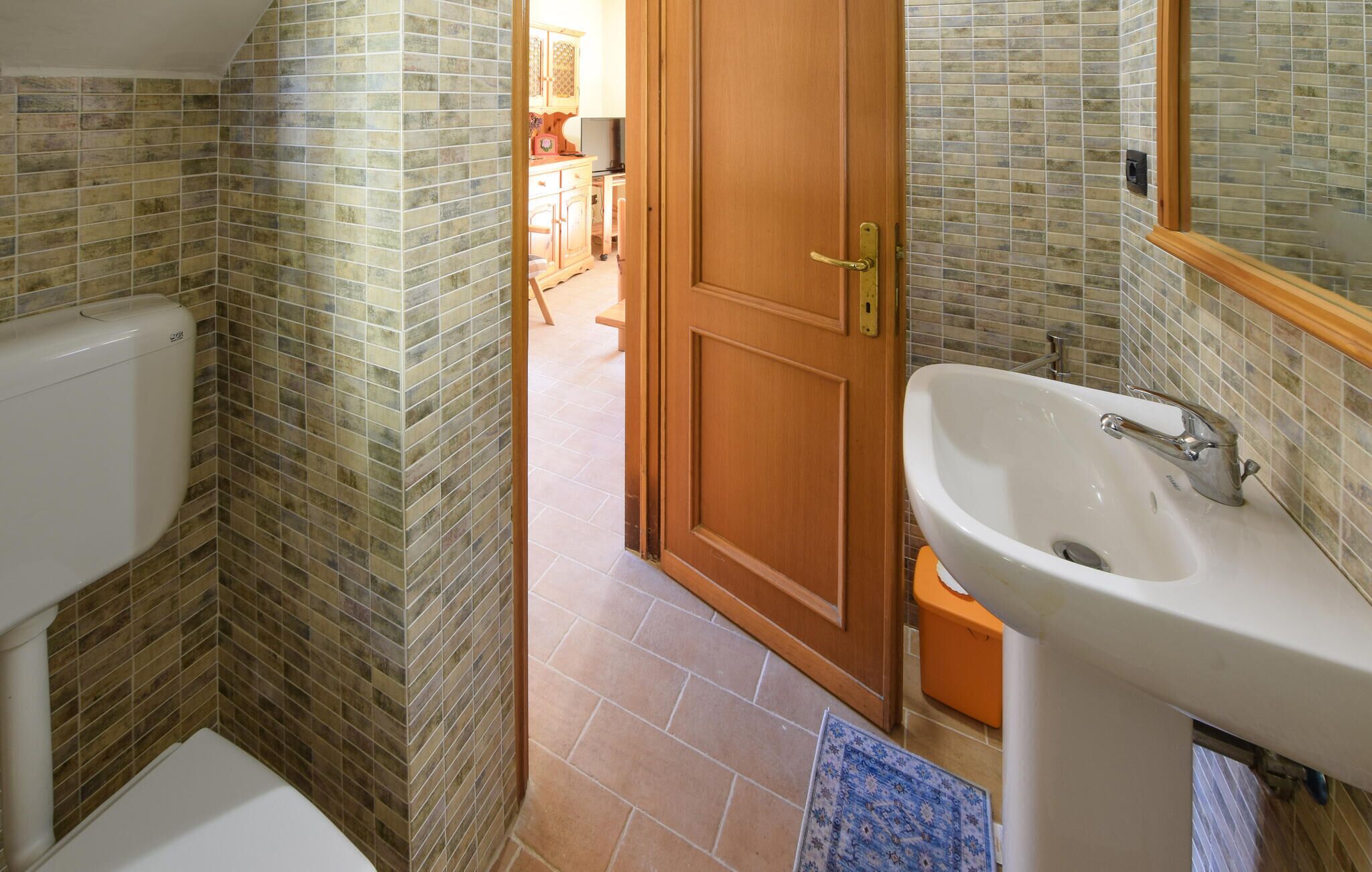 Ein Badezimmer mit Toilette, Waschbecken und gefliesten Wänden.