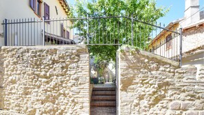 A stone staircase leading to a door with a metal gate, surrounded by buildings with traditional architecture.
