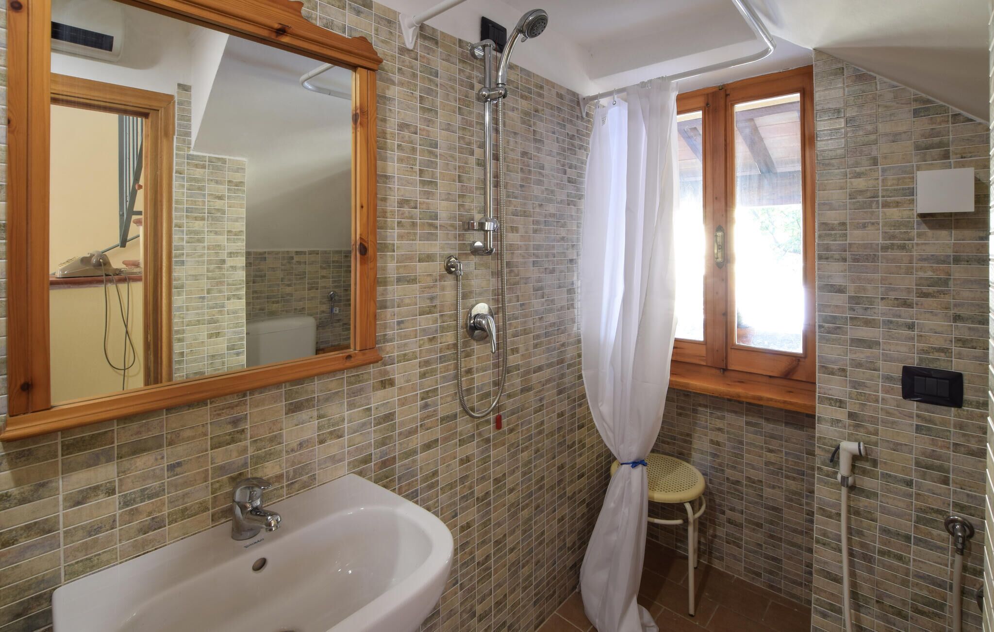 Ein Badezimmer mit Dusche, Waschbecken, Spiegel und Fenster.