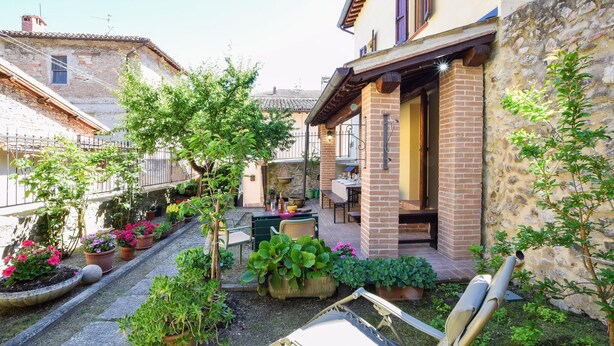 A courtyard with a dining area, potted plants, and a chair.