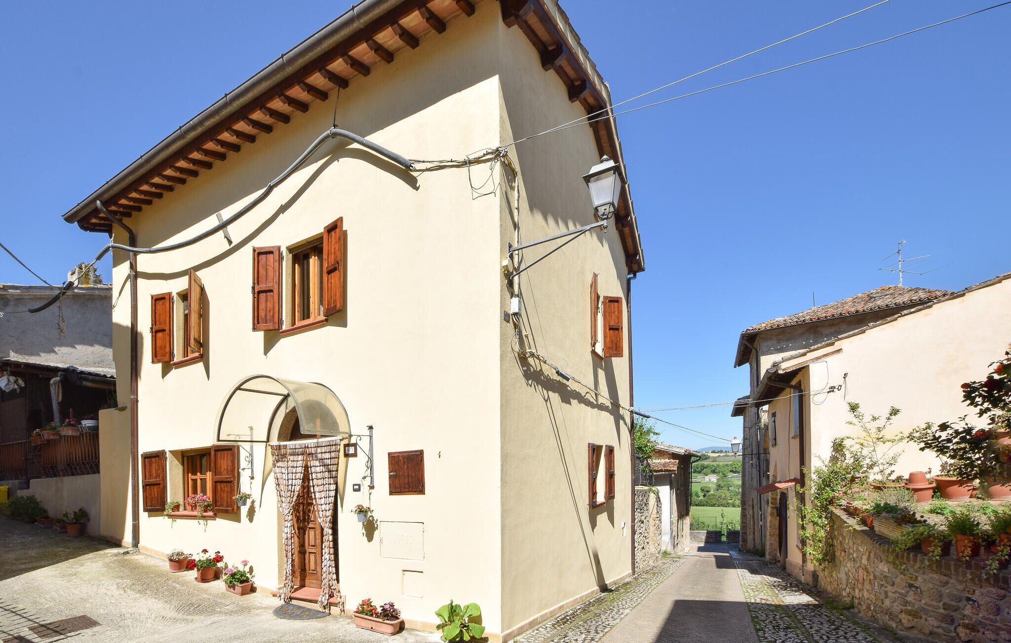 A two-story building with a tiled roof, a central entrance with a wooden door, and multiple windows with shutters.