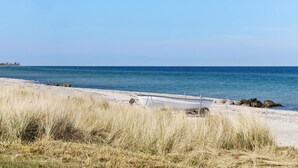 A beach with a boat tied to the shore, clear blue water, and distant land. - 2 bedroom cozy home in Otterup (Otterup)