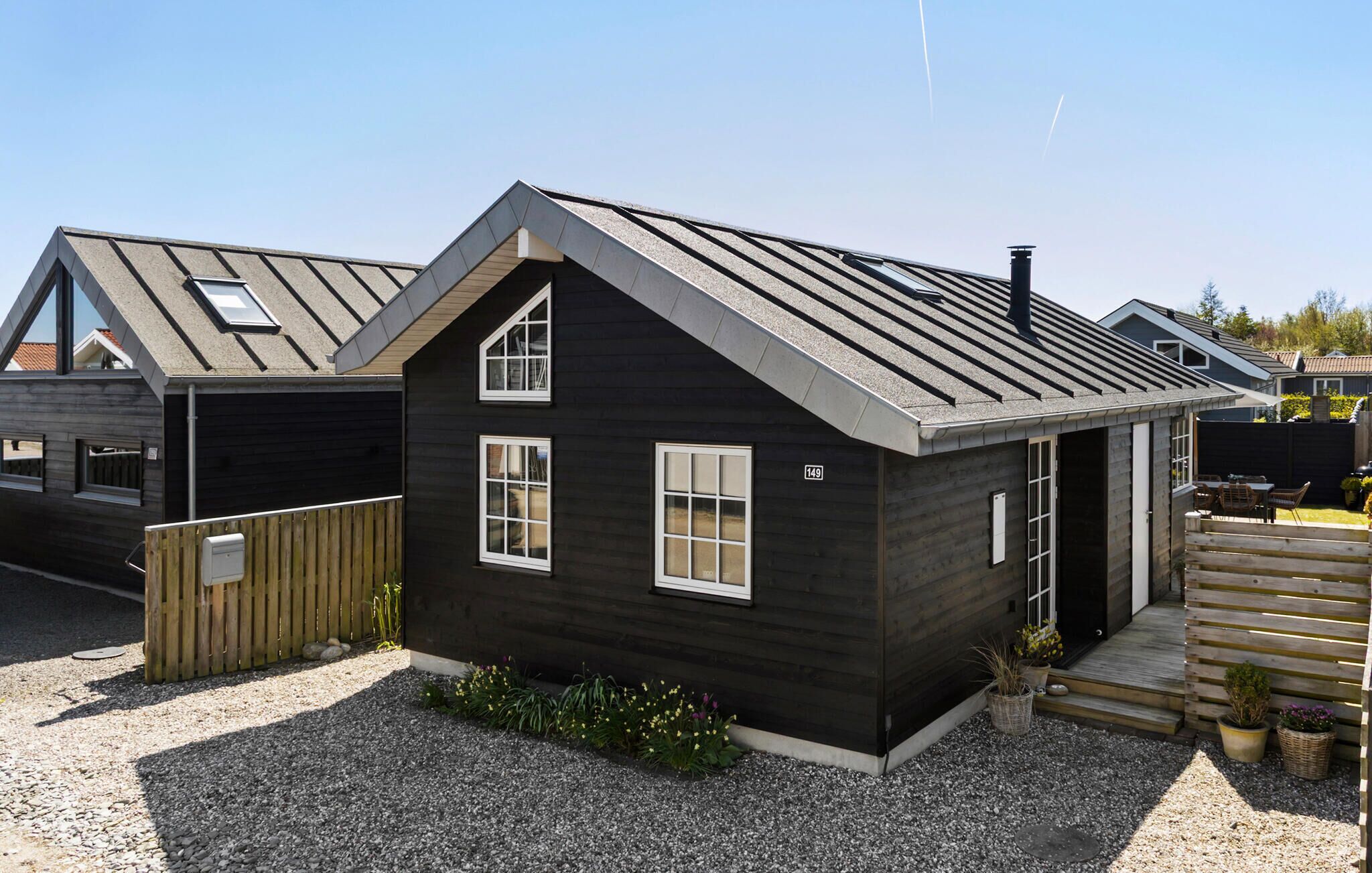 A small, dark-colored house with a sloped roof, two windows, and a number '149' on the wall.