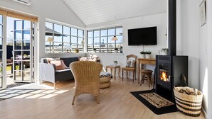 A modern living room with a fireplace, large windows, and a cozy seating area. - 2 bedroom cozy home in Otterup (Otterup)