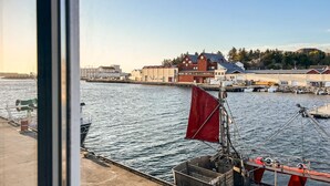 A harbor with boats, a red sail, and buildings in the background. - 3 bedroom beautiful home in Sirevåg (Sirevåg)