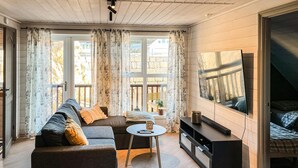 A cozy living room with a sofa, coffee table, and a TV mounted on the wall. - 3 bedroom beautiful home in Sirevåg (Sirevåg)