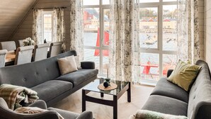 A cozy living room with a grey sofa, a small coffee table, and a view of a harbor with boats. - 3 bedroom beautiful home in Sirevåg (Sirevåg)