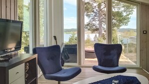 A modern room with a TV, two chairs, a guitar, and a view of a lake and trees. - Beautiful home in Trøgstad (Trøgstad)