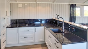 A modern kitchen with white cabinetry, black countertops, and a stainless steel sink. - Beautiful home in Trøgstad (Trøgstad)