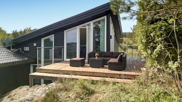 A modern house with a deck, large sliding glass doors, and outdoor furniture. - Beautiful home in Trøgstad (Trøgstad)