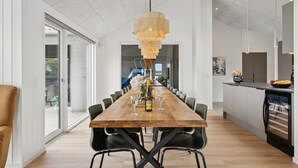 A modern dining area with a wooden table, black chairs, and a unique hanging light fixture.