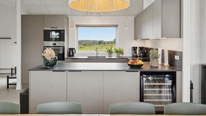 A modern kitchen with a central island, built-in appliances, and a large window offering a view of the outdoors.