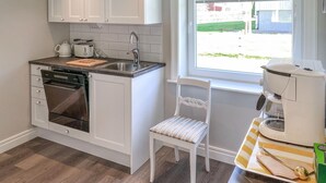 A compact kitchen with white cabinets, a dishwasher, a coffee machine, and a window with a view of the outside. - Cozy home in Ormaryd with WiFi (Ormaryd)