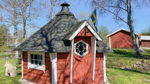 A small red wooden cabin with a black roof, a white door, and a window with a white frame. - Cozy home in Ormaryd with WiFi (Ormaryd)