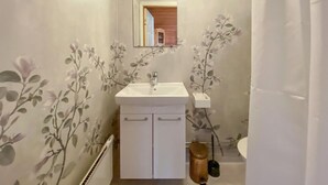 Ein Badezimmer mit einem weißen Waschbecken, einem kleinen Schrank und einem Spiegel.