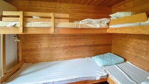 Eine gemütliche Holzhütte mit Etagenbetten, einem kleinen Kleiderschrank und einem roten Teppichboden.