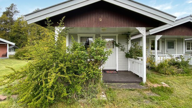 Ein zweistöckiges Haus mit einer Veranda und einem kleinen Vorgarten.