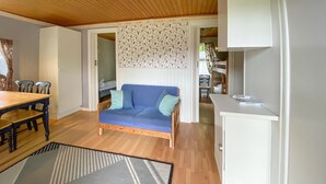 A cozy room with a wooden dining table, a blue sofa with cushions, and a white cabinet.