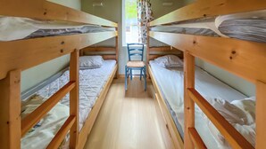 A narrow corridor with bunk beds on either side and a chair in the center.